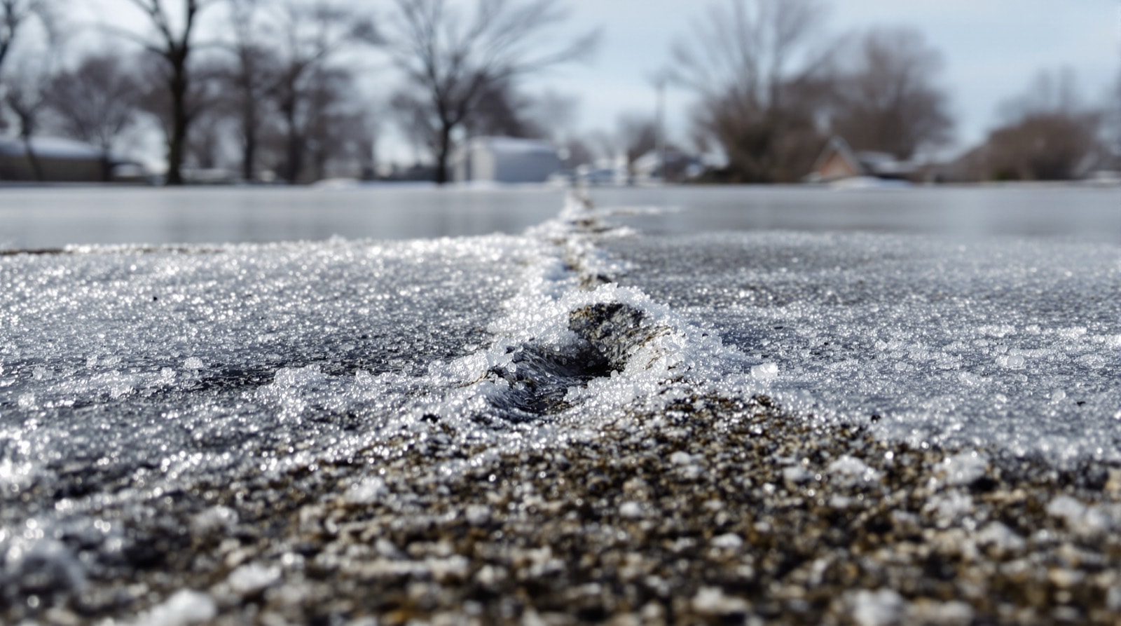 Frost on a concrete pavement with surface scaling damage visible at one edge